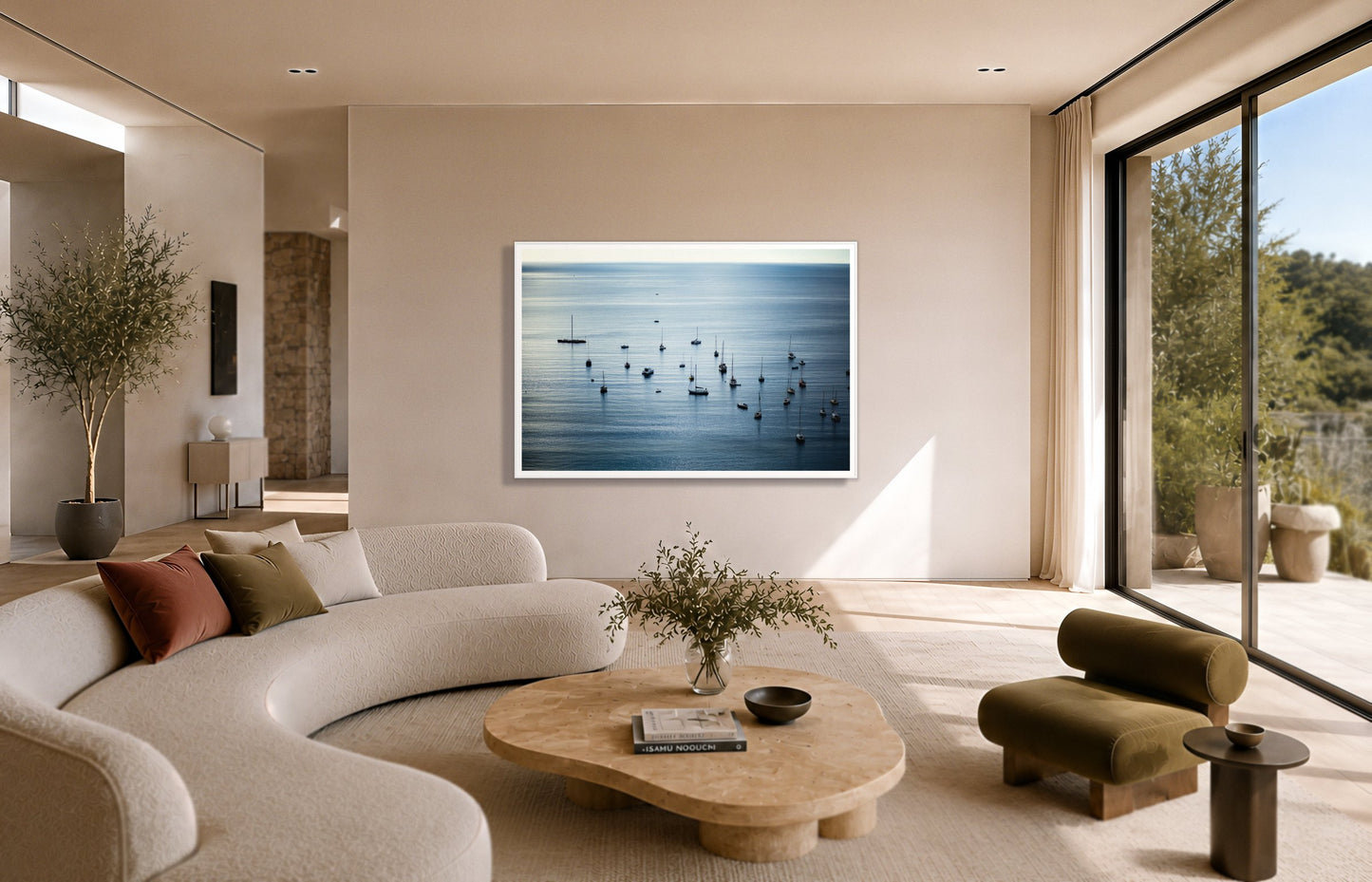 Sea Scape by Dylan Ozanich in a White frame, above a cream curved sofa in a sunlit room with olive velvet seating