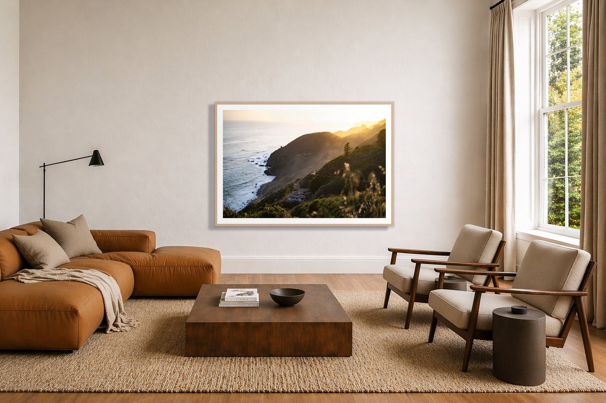 Big Sur Sunset by Dylan Ozanich in an Oak frame, above a tan modular leather sofa in a minimal, sunlit living room