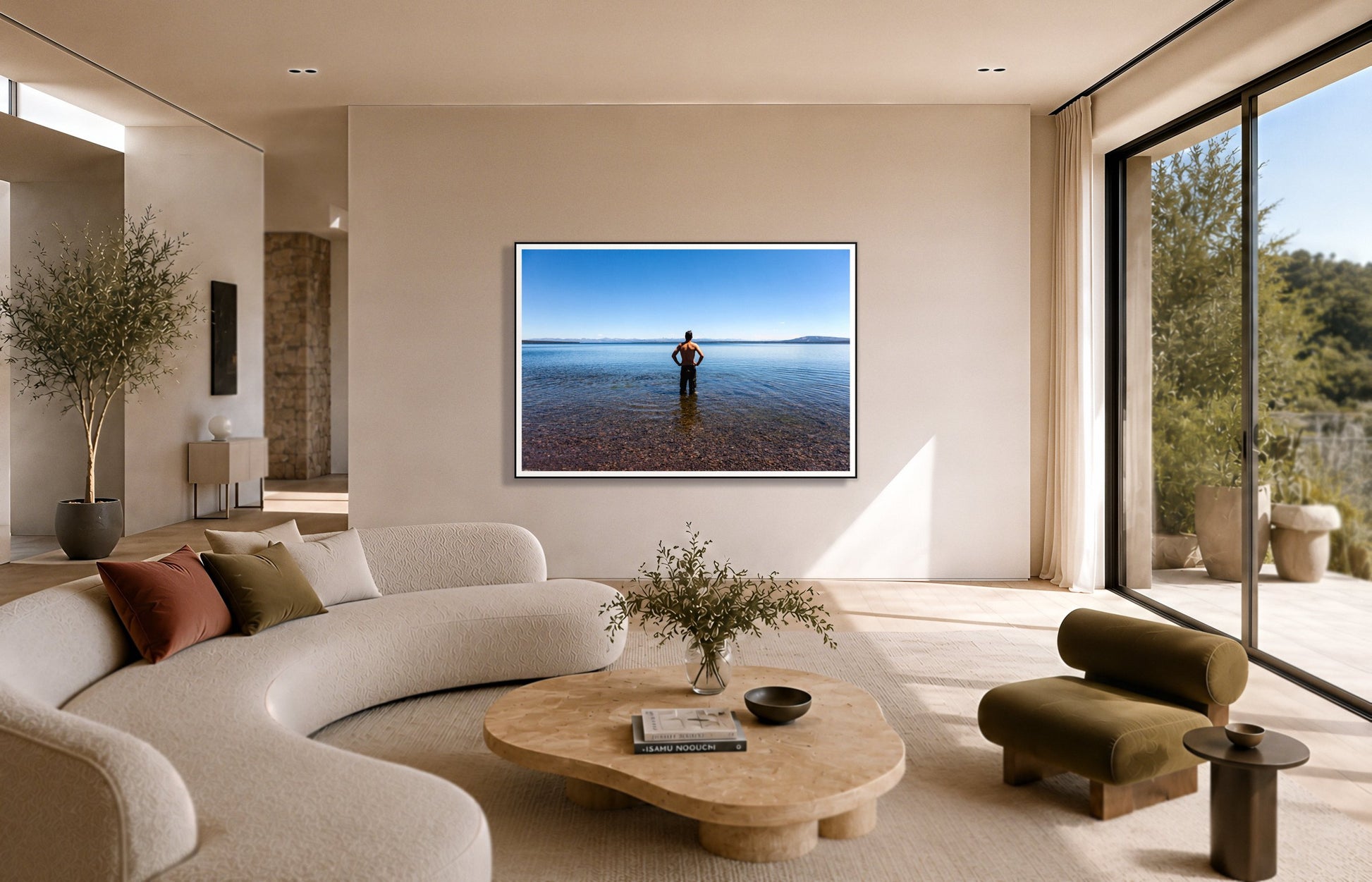 Cool Off by Dylan Ozanich in a Black frame, above a cream curved sofa in a sunlit room with olive velvet seating
