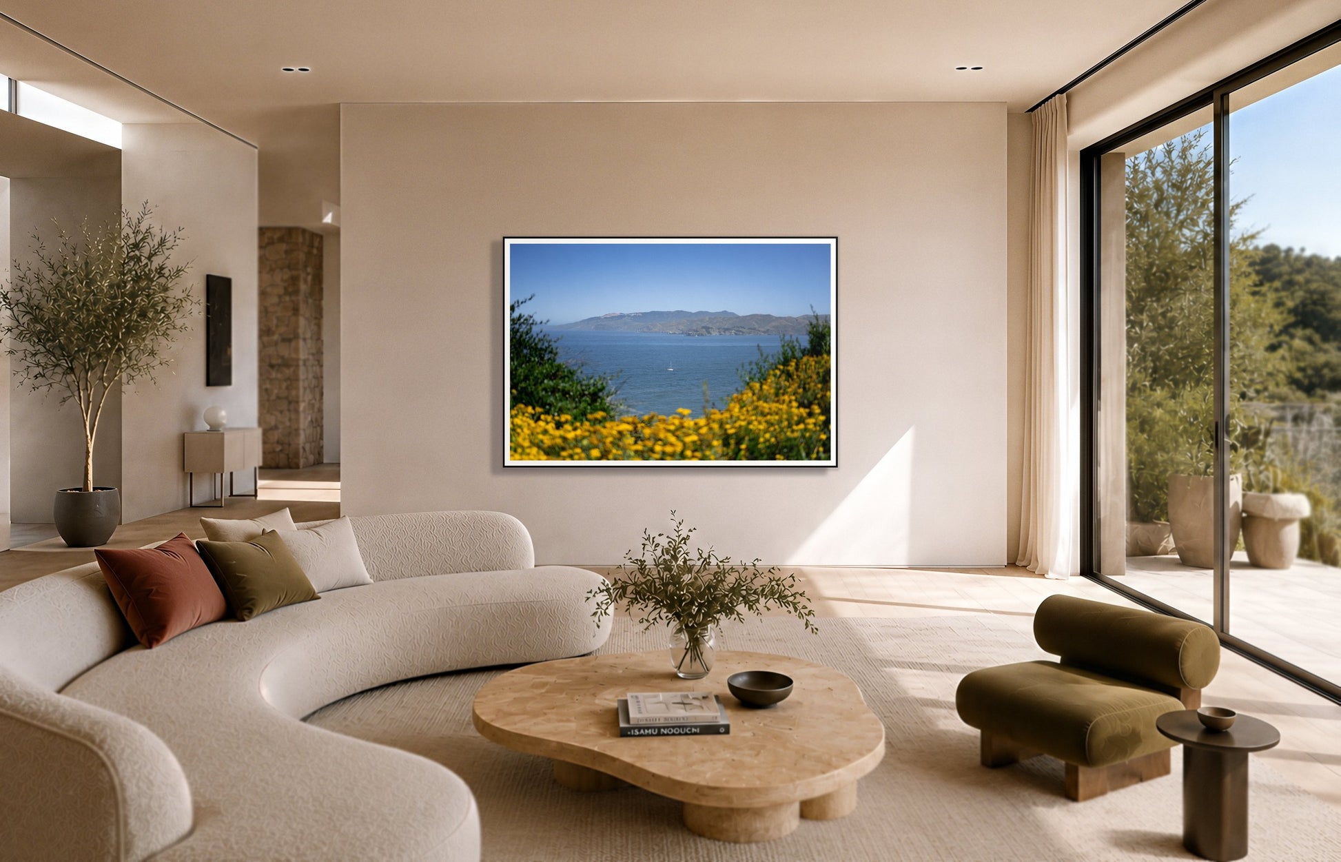 Golden Bay by Dylan Ozanich in a Black frame, above a cream curved sofa in a sunlit room with olive velvet seating