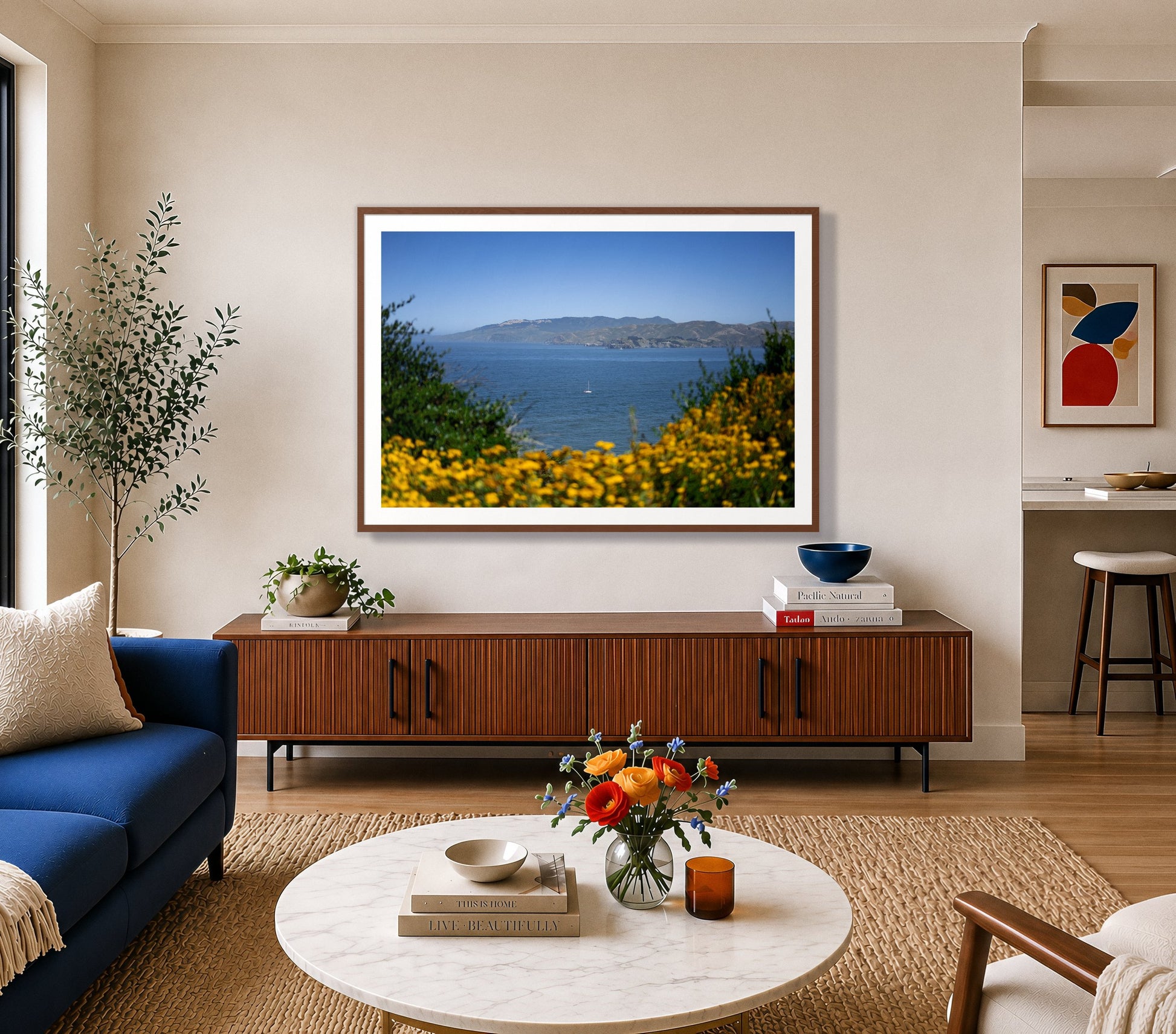 Golden Bay by Dylan Ozanich in a Walnut frame, above a walnut credenza in a bright living room with a blue sofa