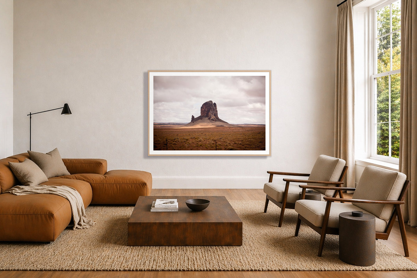 Nowhere New Mexico by Dylan Ozanich in an Oak frame, above a tan modular leather sofa in a minimal, sunlit living room