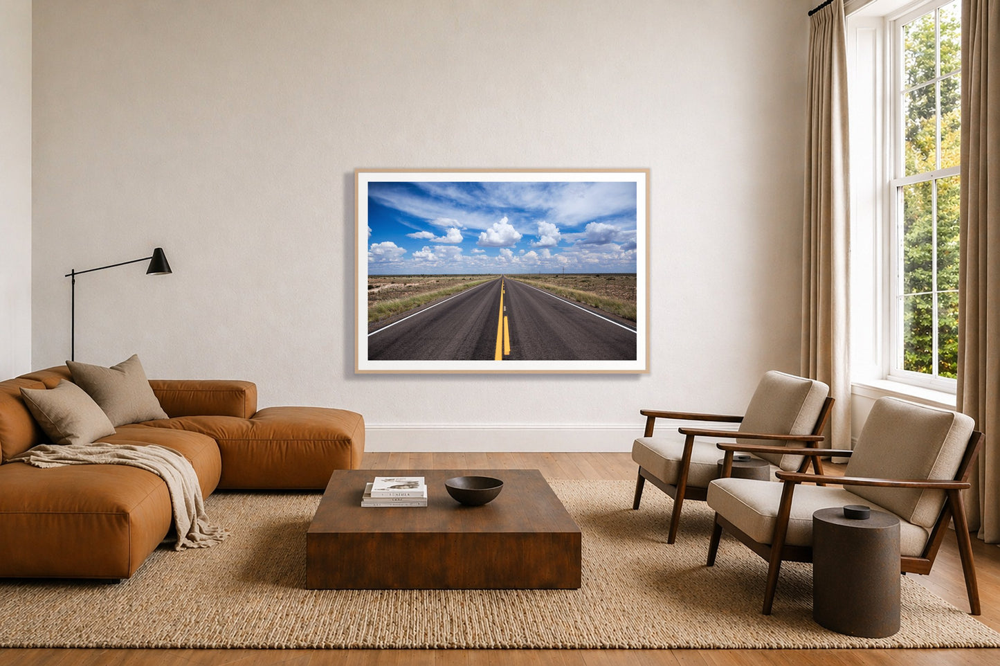 Open Road by Dylan Ozanich in an Oak frame, above a tan modular leather sofa in a minimal, sunlit living room
