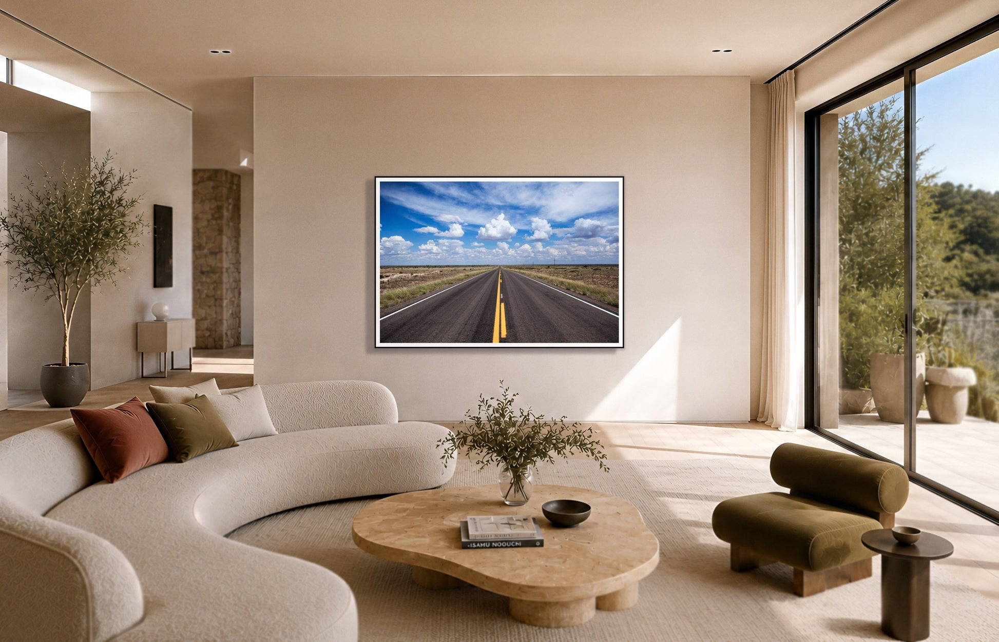 Open Road by Dylan Ozanich in a Black frame, above a cream curved sofa in a sunlit room with olive velvet seating