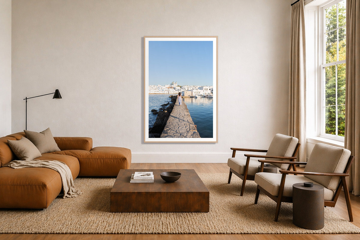 Path To Paros by Dylan Ozanich in an Oak frame, above a tan modular leather sofa in a minimal, sunlit living room