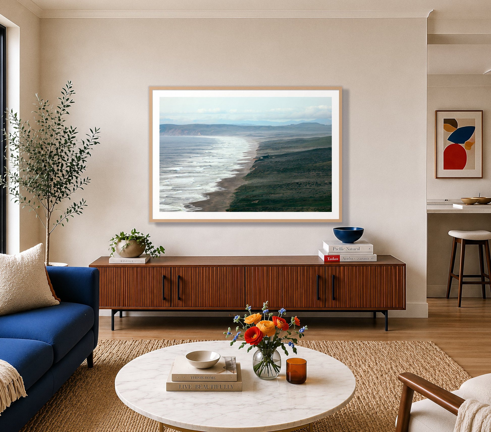 Point Reyes Ranch by Dylan Ozanich in an Oak frame, above a walnut credenza in a bright living room with a blue sofa