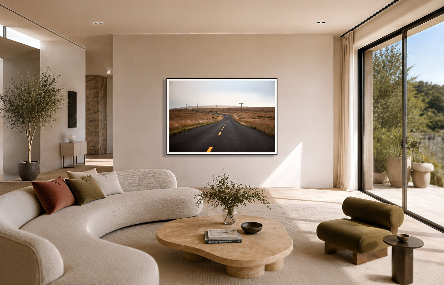 Point Reyes by Dylan Ozanich in a Black frame, above a cream curved sofa in a sunlit room with olive velvet seating