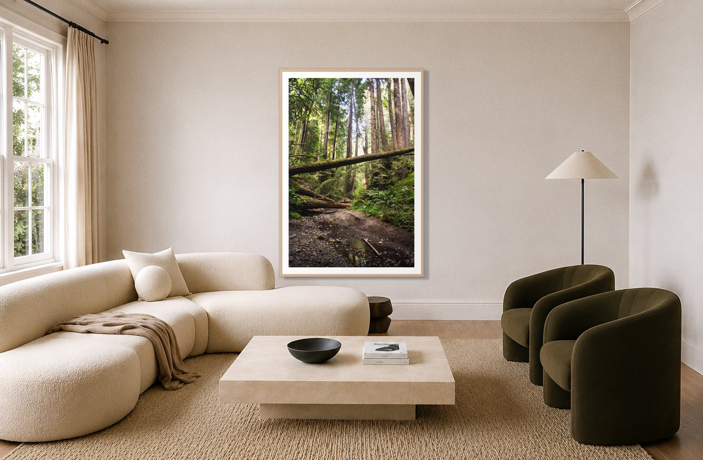 Redwoods California by Dylan Ozanich in an Oak frame, above a cream curved sofa in a living room with olive velvet armchairs