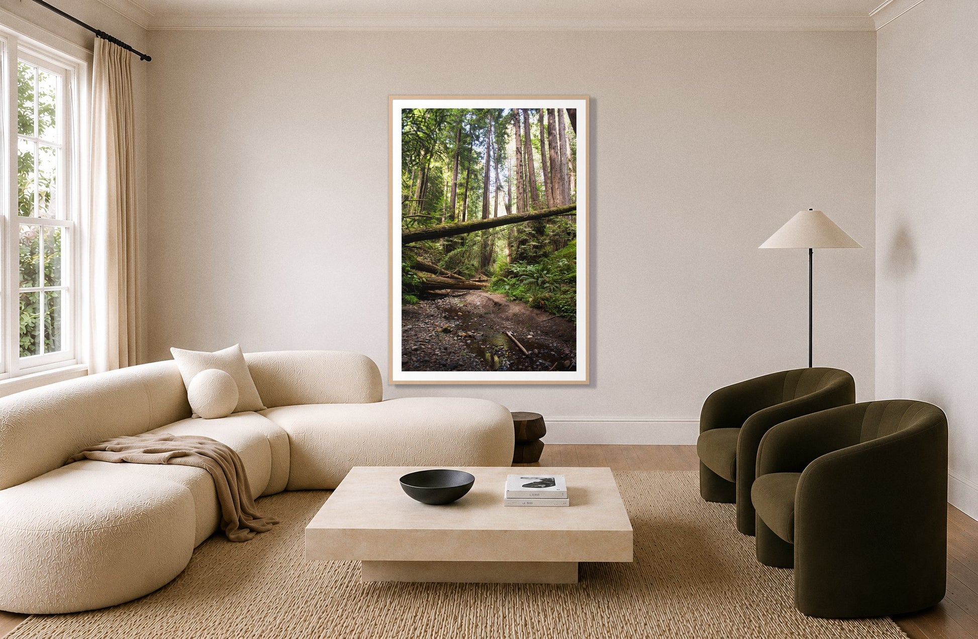 Redwoods California by Dylan Ozanich in an Oak frame, above a cream curved sofa in a living room with olive velvet armchairs