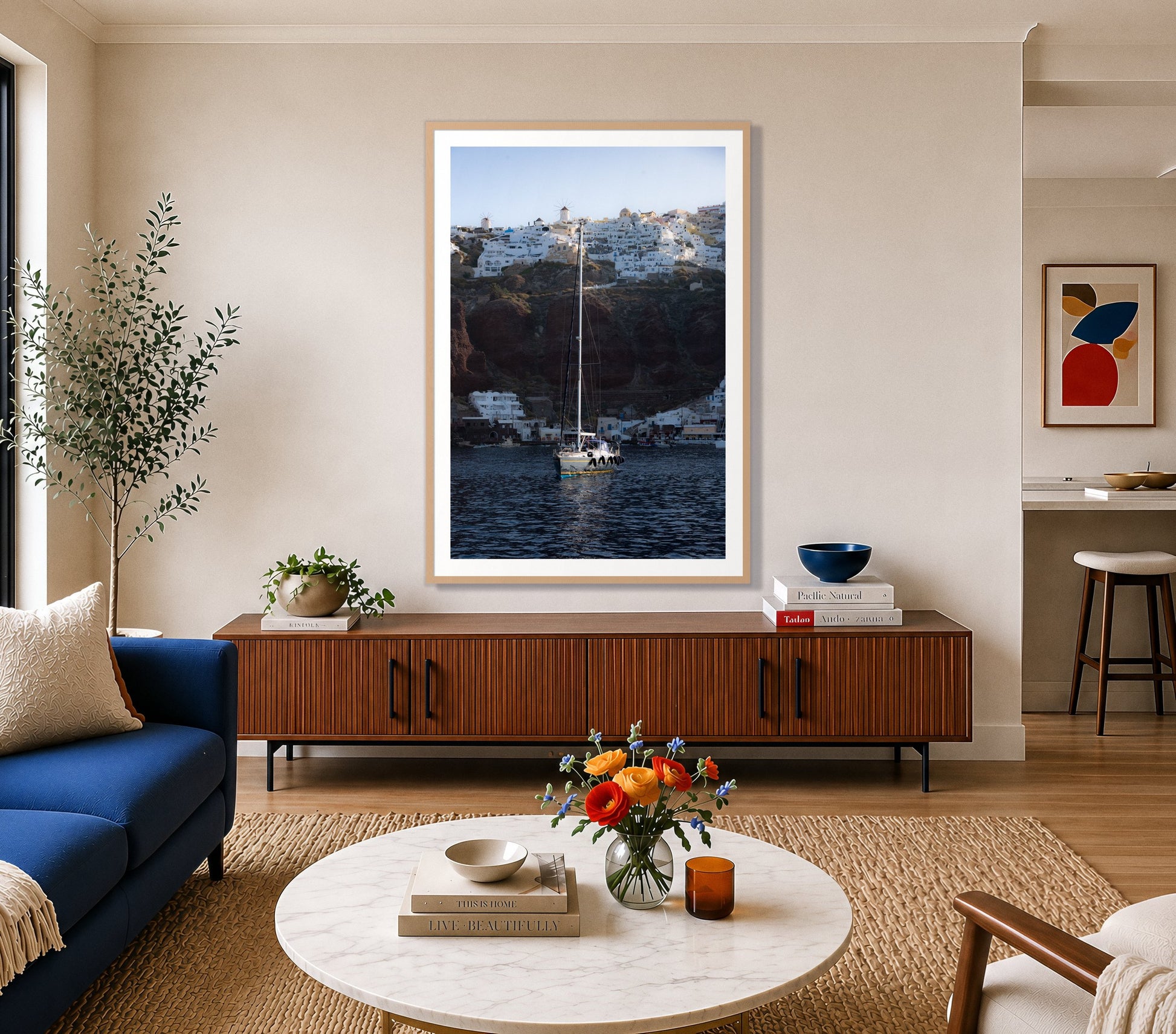 Sailing In Greece by Dylan Ozanich in an Oak frame, above a walnut credenza in a bright living room with a blue sofa
