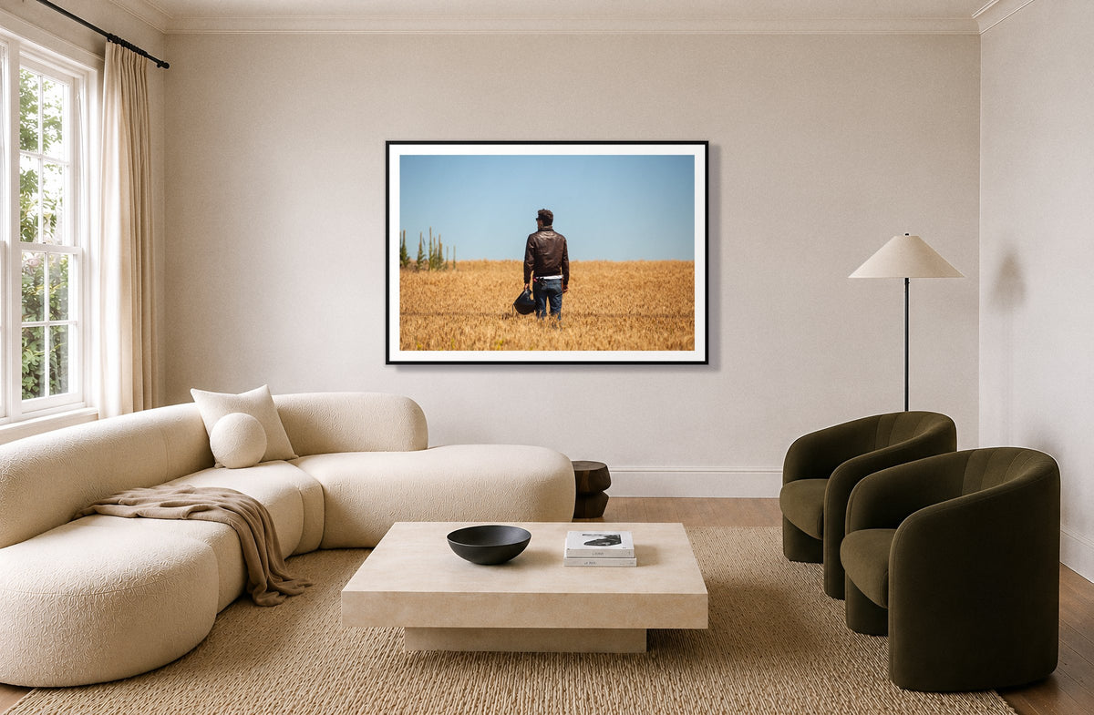 Wonderlust by Dylan Ozanich in a Black frame, above a cream curved sofa in a living room with olive velvet armchairs